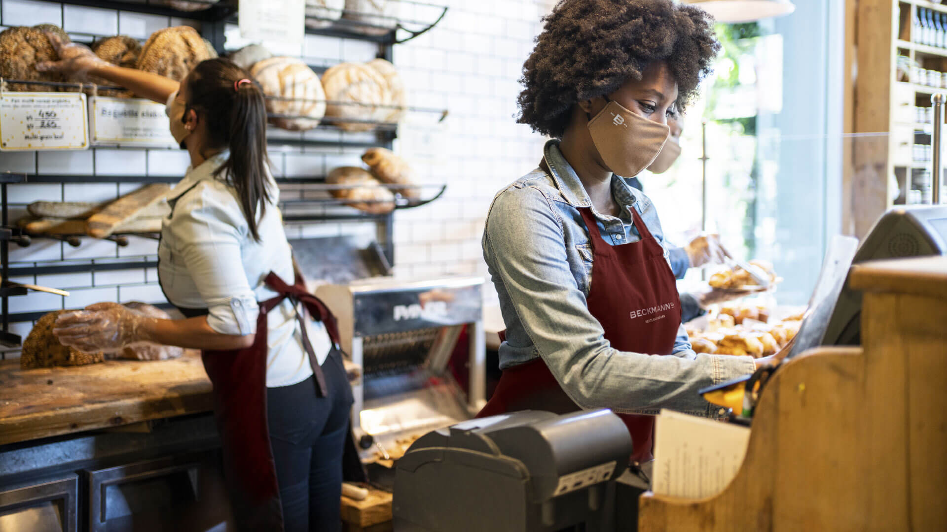 Angestellte der Bäckerei mit Mundschutz im Corporate Design der Bäckerei Beckmanns