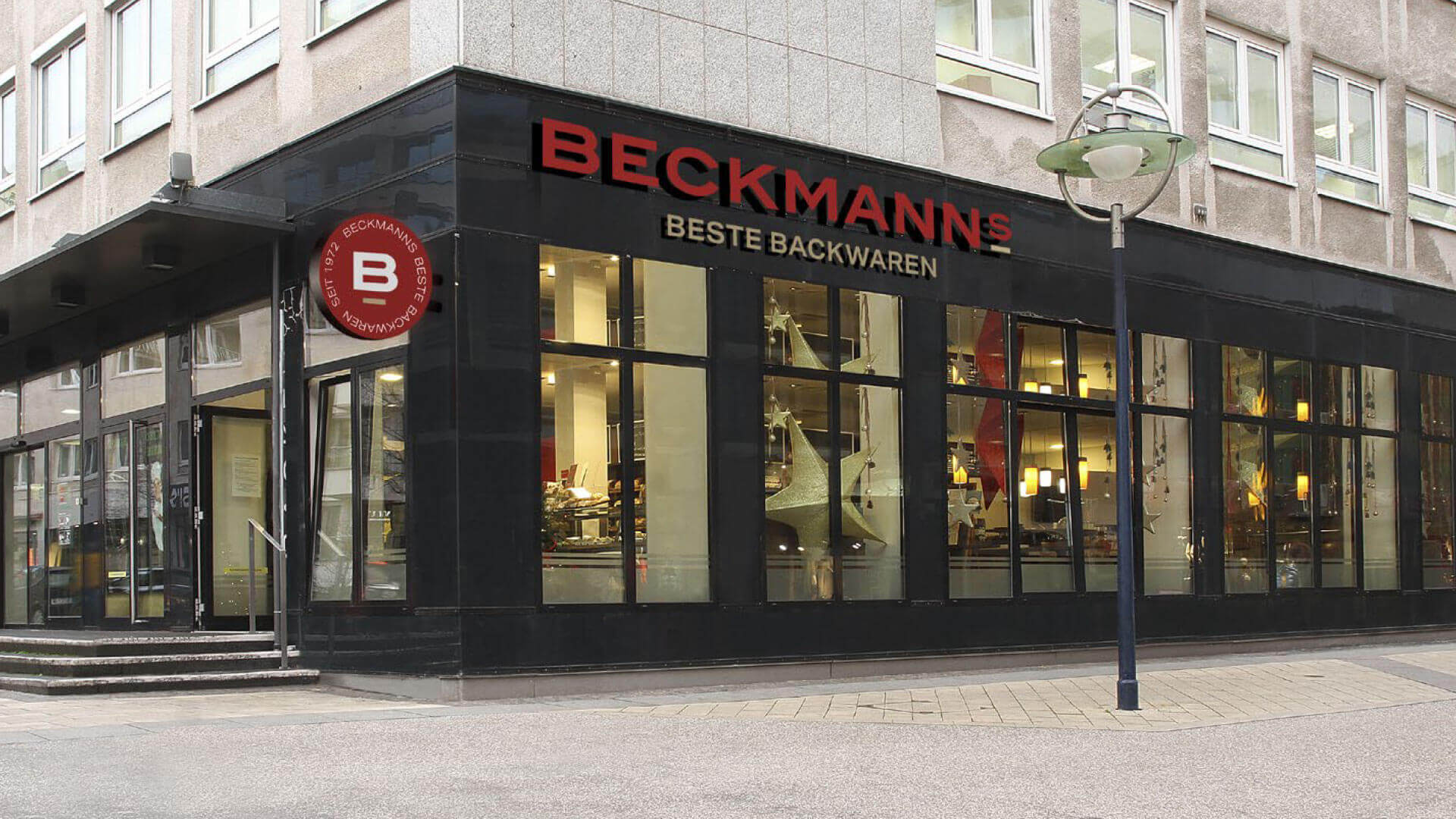 Moderne Ladenfassade von Bäcker Beckmanns in Dortmund mit rotem Logo auf schwarzer Glasfront, umgesetzt im Corporate Design.
