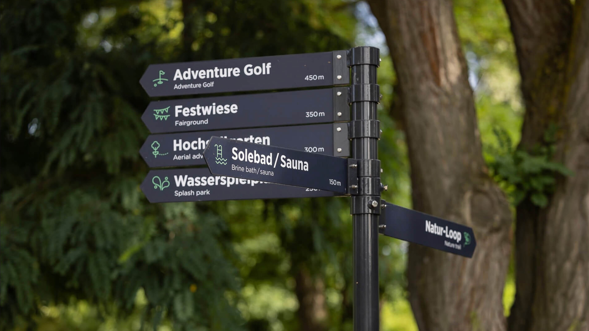 Detailaufnahme eines Wegweisers im Knotenpunktsystem des RVR mit mehreren Schildern, Icons, zweisprachiger Beschriftung und Entfernungsangaben zu den jeweiligen Zielen – umgesetzt von Florida Brand Design.