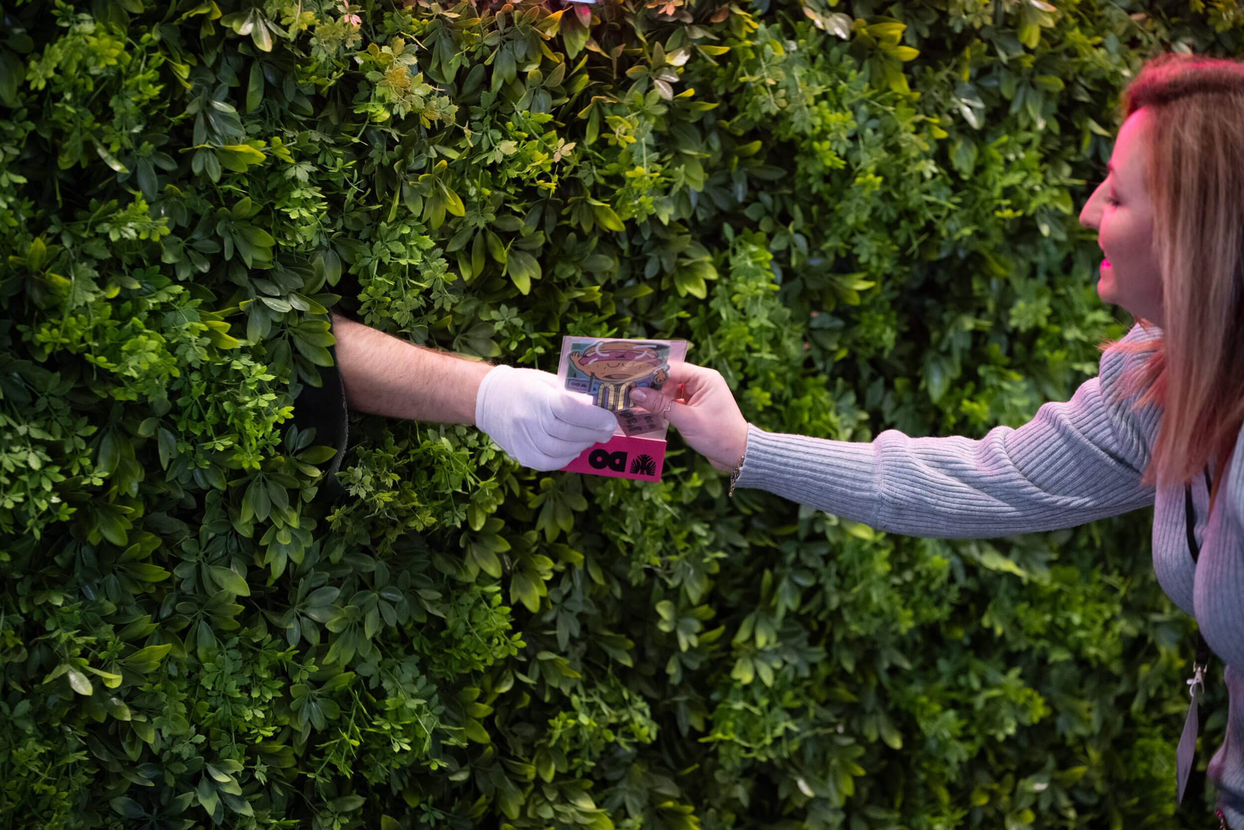 Besucherin erhält Sticker-Giveaway aus einer Living-Hedge-Installation auf der BOE Messe zur Aktivierung der Dortmunder Stadtmarke